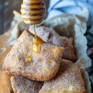 Honey dipper drizzling honey onto a sopaipilla