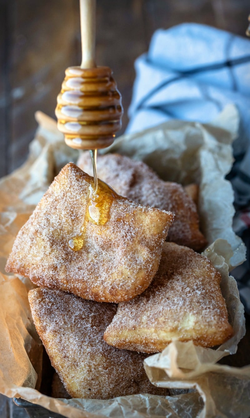 Honey dipper drizzling honey onto a sopaipilla