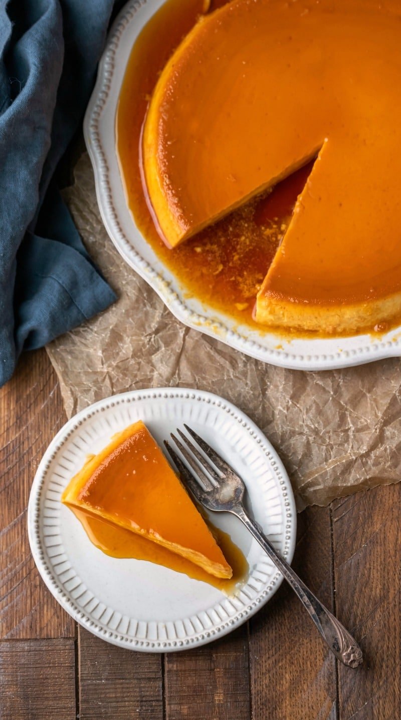 Slice of flan de queso on a plate on a wooden background