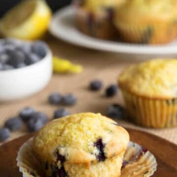 A blueberry lemon ricotta muffin on a wooden plate.