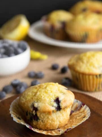 A blueberry lemon ricotta muffin on a wooden plate.