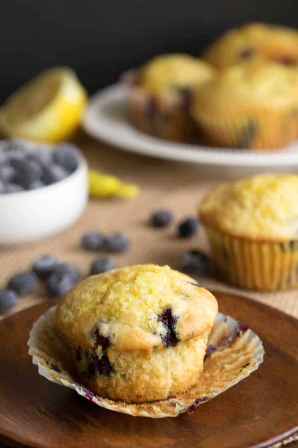 A blueberry lemon ricotta muffin on a wooden plate. 