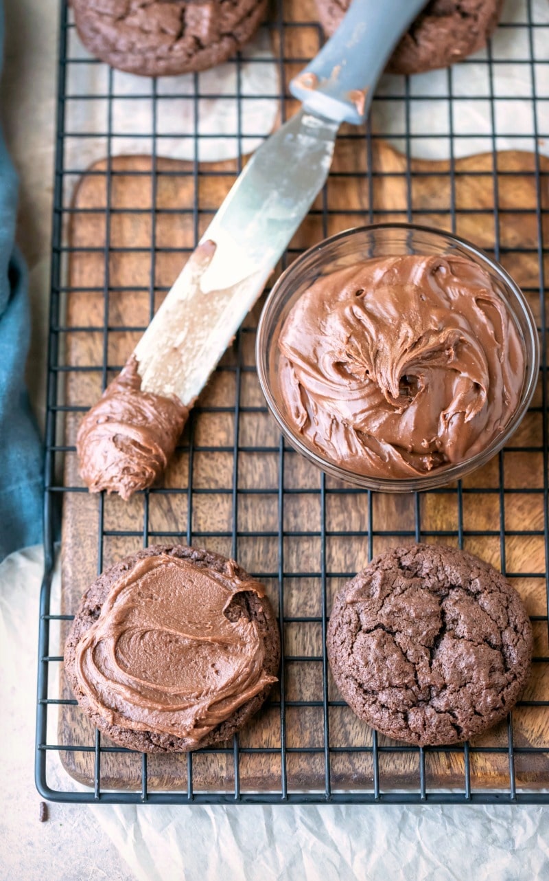 Chocolate frosted cookie next to a dish of chocolate frosting