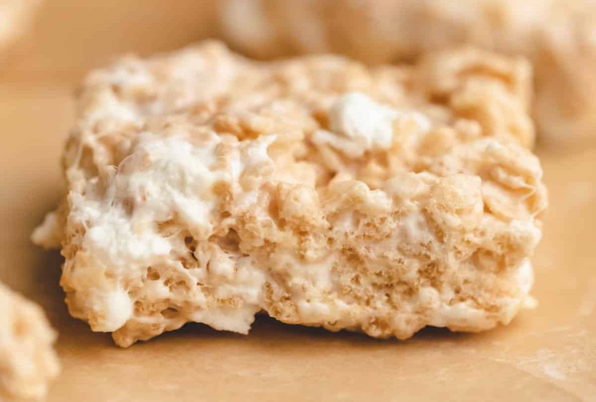 A rice krispie treat from the side on a piece of brown parchment paper.