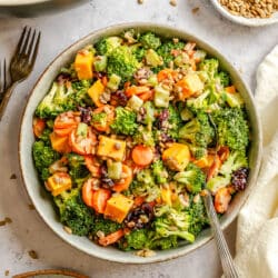 A bowl of broccoli salad next to a dish of sunflower seeds.