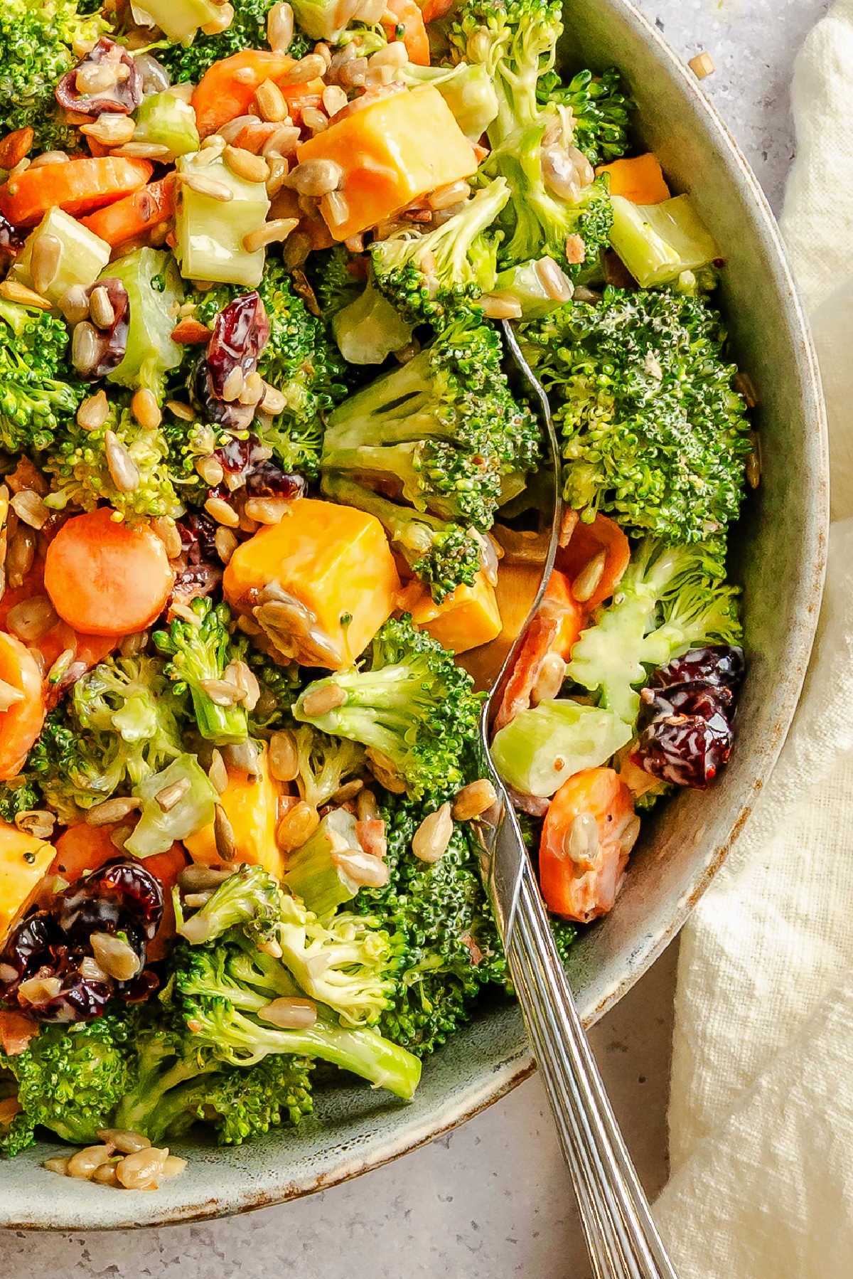 Close up of a bowl of broccoli salad with a serving spoon in it. 