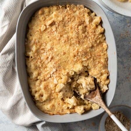 A pan of cauliflower mac and cheese with a wooden spoon in it.