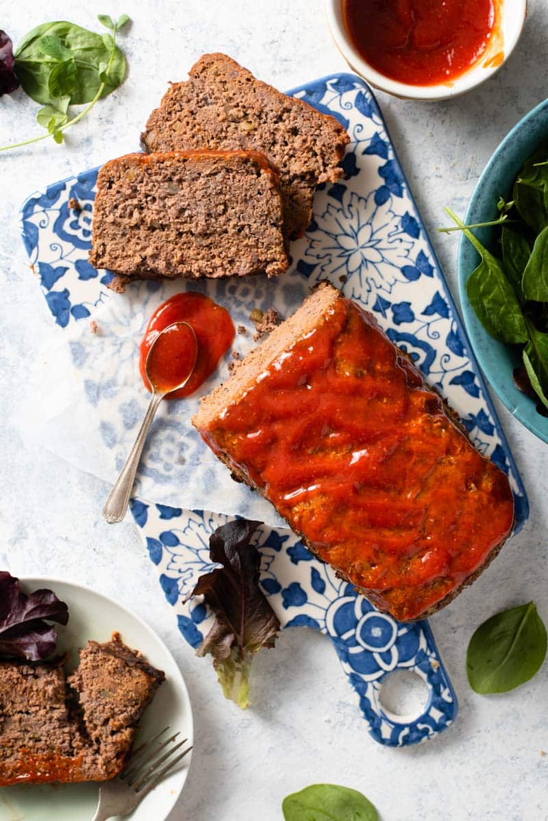 An overhead shot of an easy meatloaf on a cutting board with chili sauce 