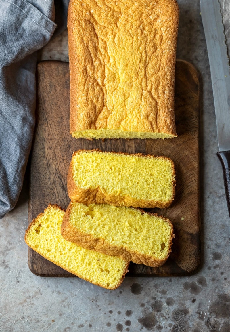 Three slices of sponge cake next to a loaf of sponge cake