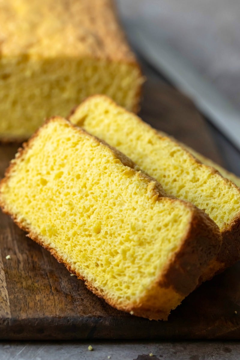 Two slices of sponge cake on a wooden cutting board