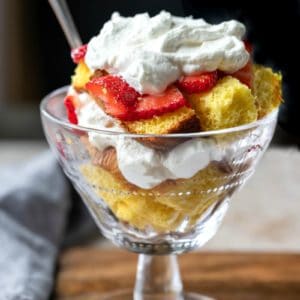 Pound cake in a glass dish topped with strawberries and whipped cream