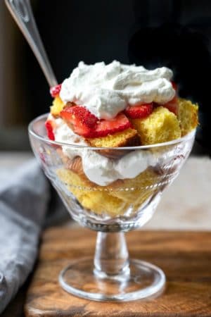 Pound cake in a glass dish topped with strawberries and whipped cream