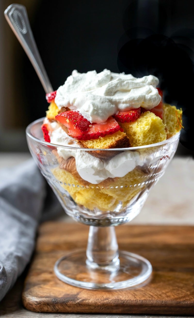 Pound cake in a glass dish topped with strawberries and whipped cream