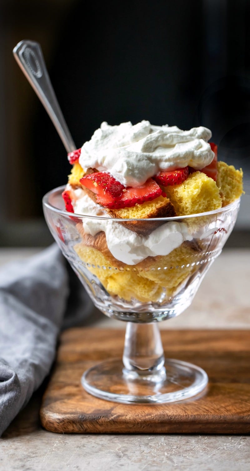 Glass parfait dish with cubes of pound cake strawberries and whipped cream