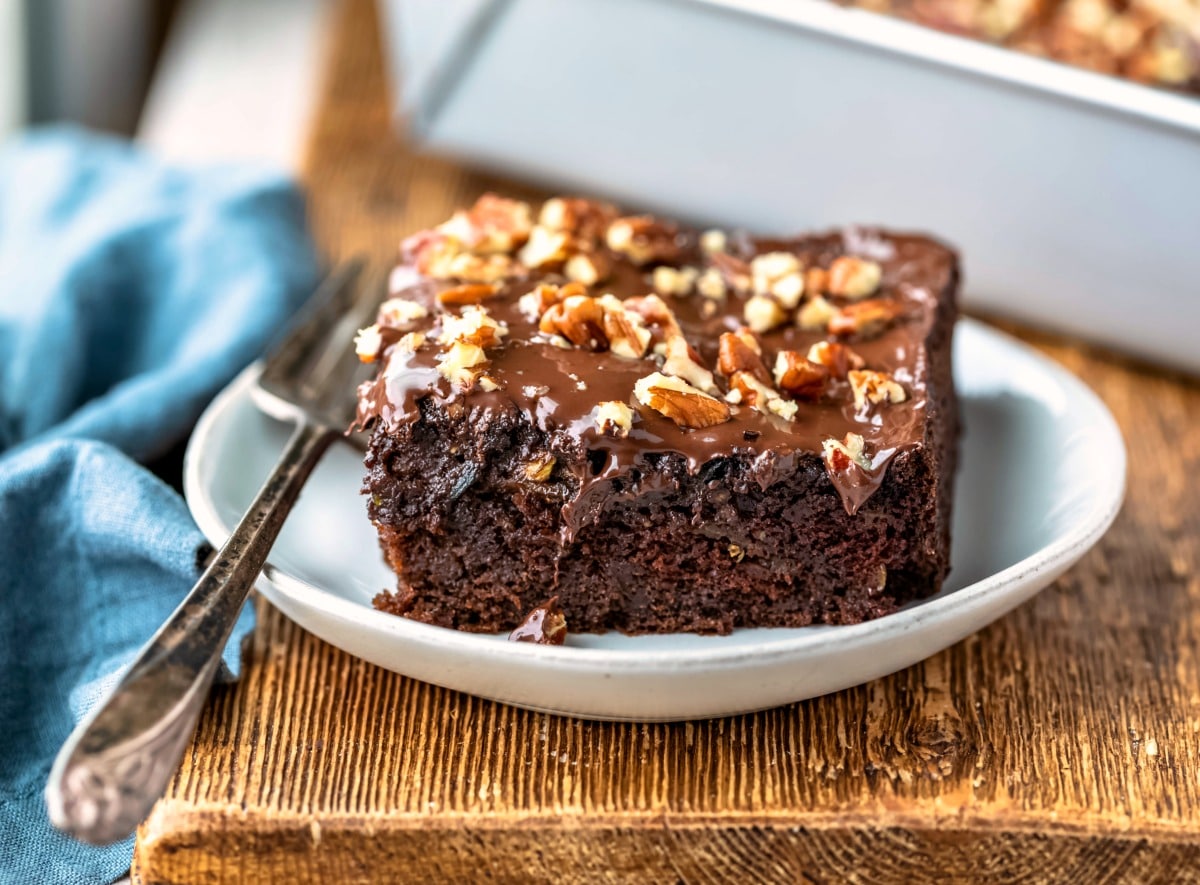 Slice of chocolate zucchini cake on a plate with a silver fork