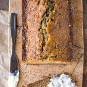 Loaf of zucchini bread with a slice cut and partially buttered.