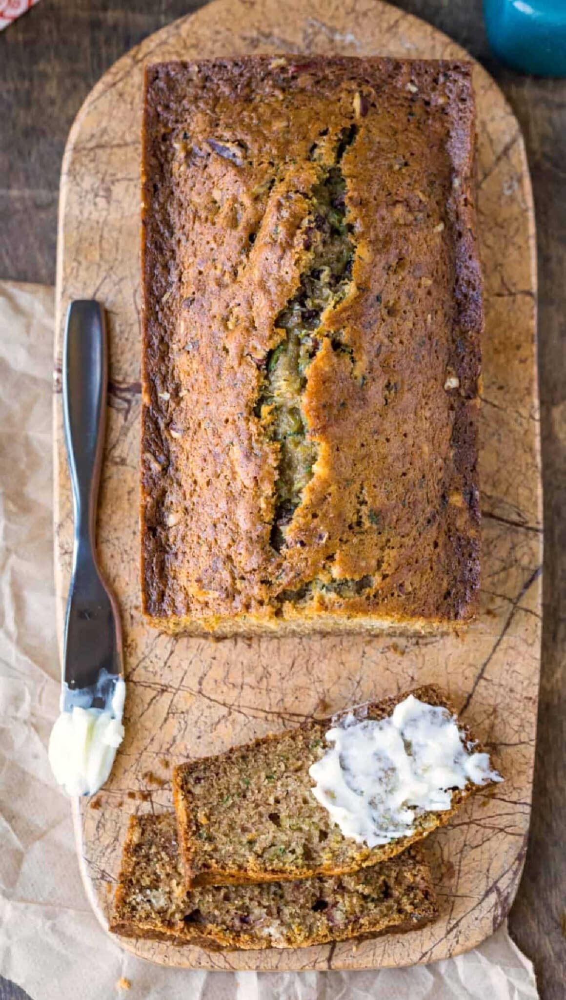 Loaf of zucchini bread with a slice cut and partially buttered.