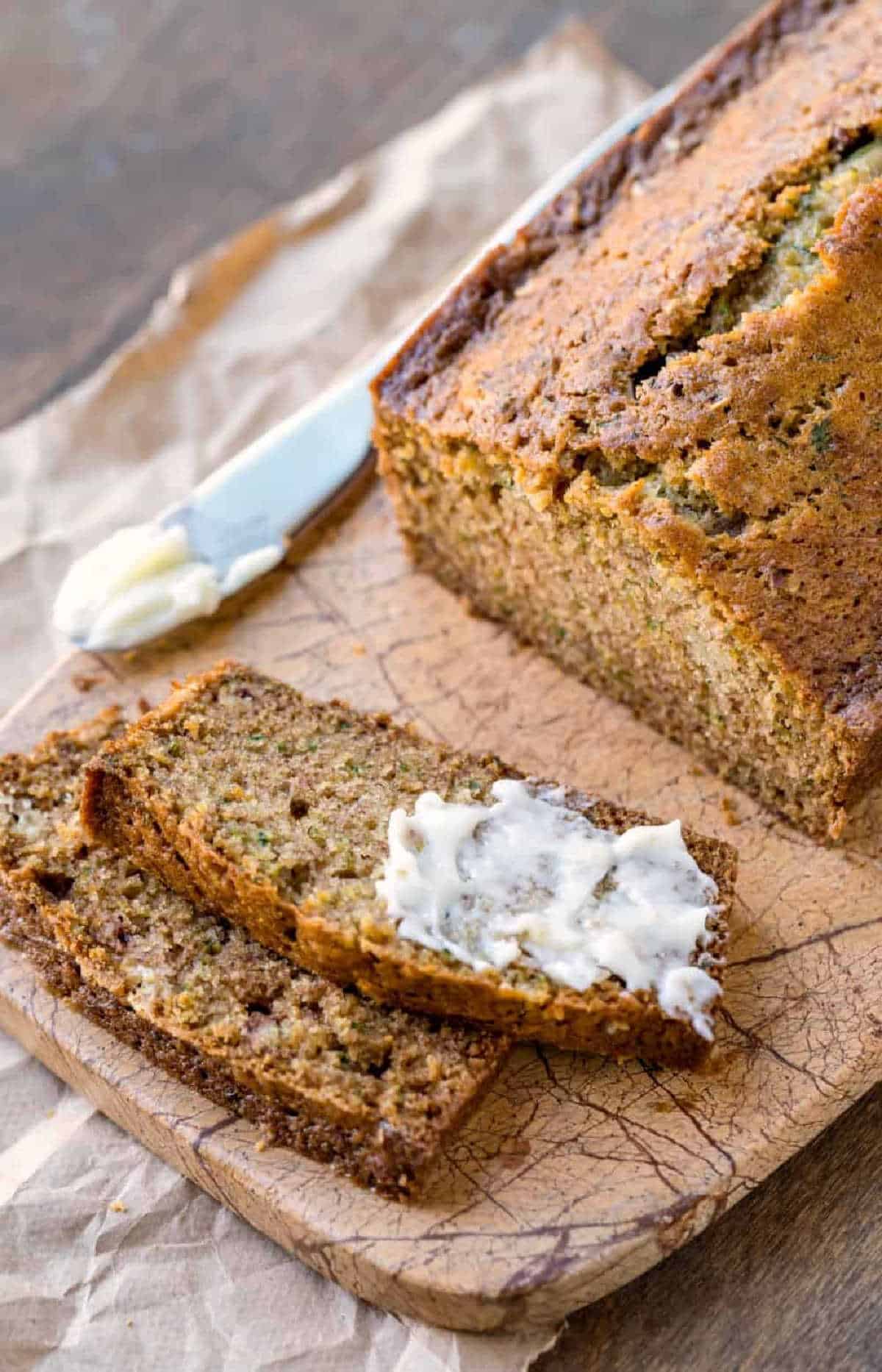 Two slices of zucchini bread on a marble cutting board. 