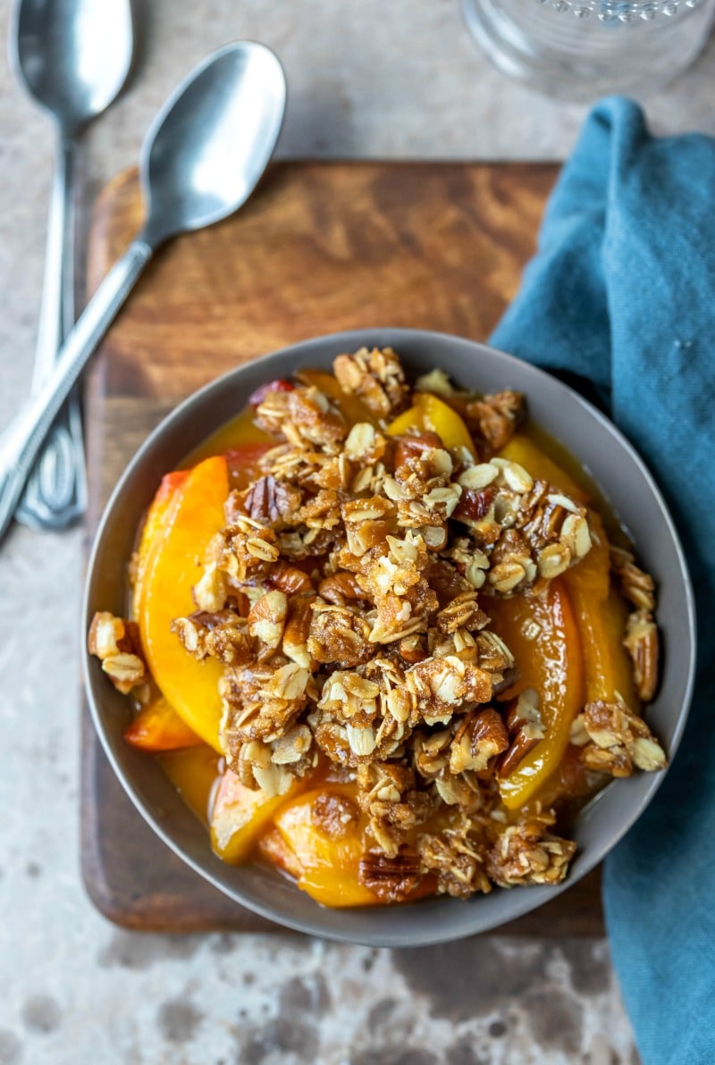 Dish of easy peach crisp on a wooden cutting board