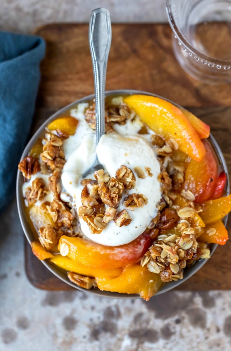 Dish of peach crisp topped with vanilla ice cream