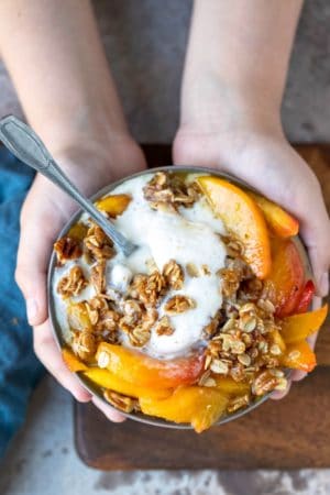 Hands holding a dish of skillet peach crisp