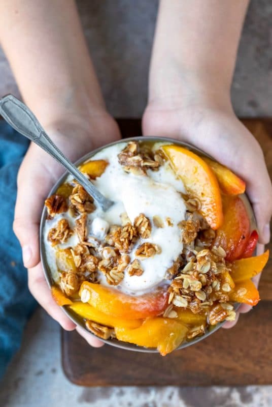 Hands holding a dish of skillet peach crisp