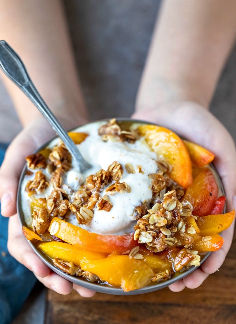 Gray dish of peach crisp and vanilla ice cream