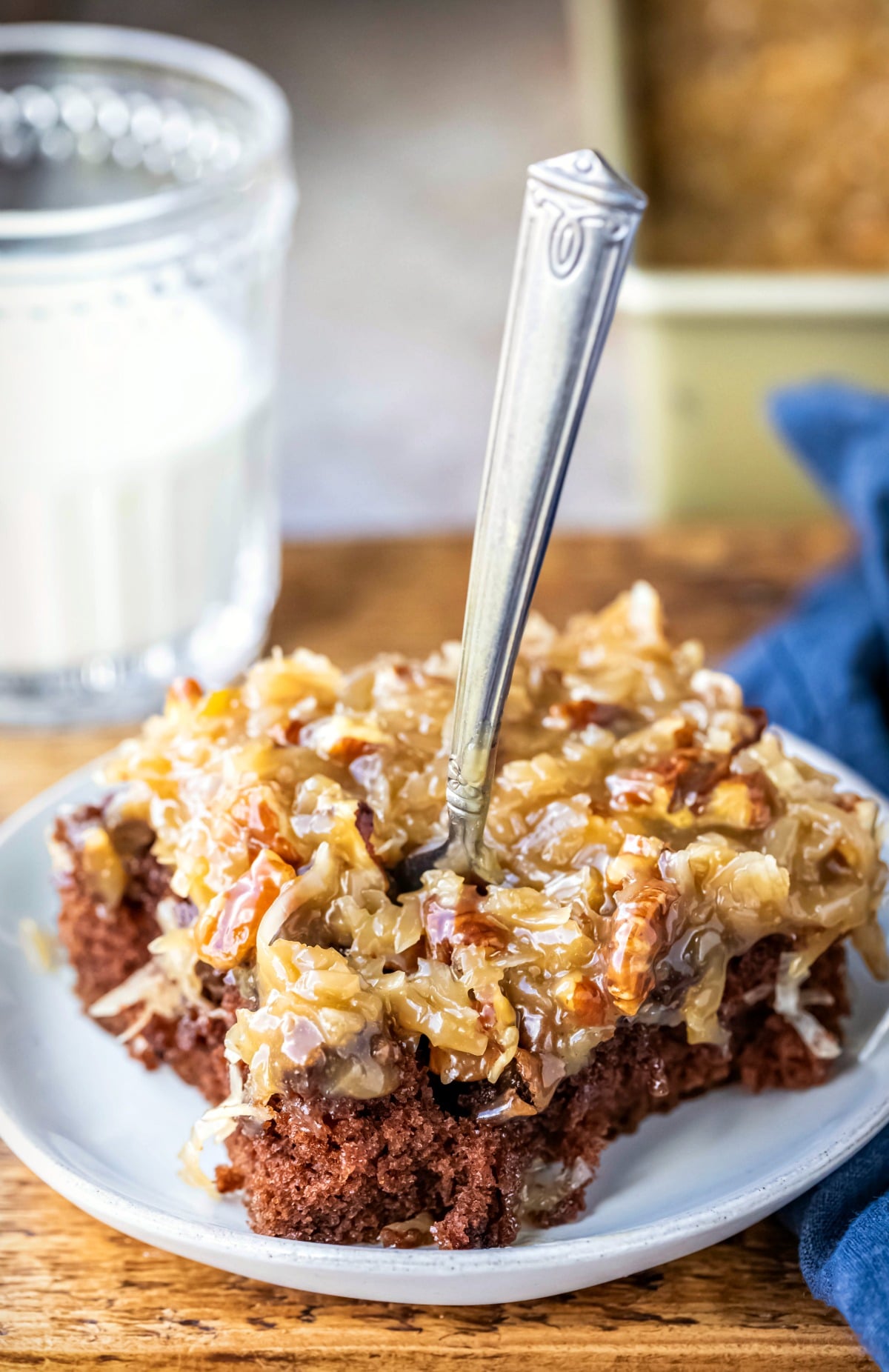 Slice of german chocolate cake with a fork taking a bite out. 