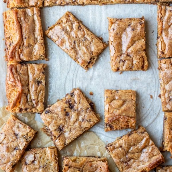 Partially cut tray of blondies on parchment paper