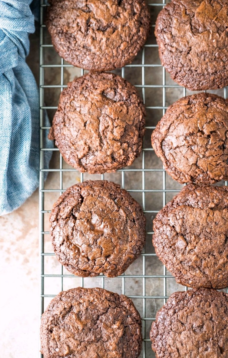 Chocolate fudge cookies on a wire cooling rack next to a blue linen napkin