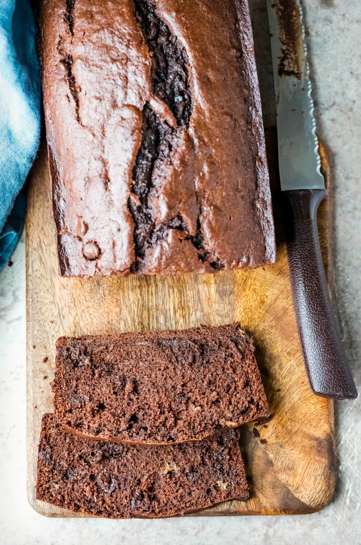 Two slices of chocolate banana bread on a wooden cutting board