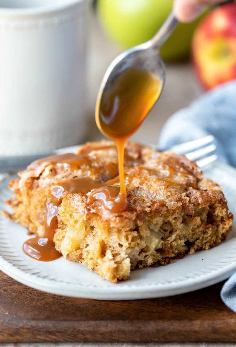 Spoon drizzling caramel on top of cinnamon apple cake
