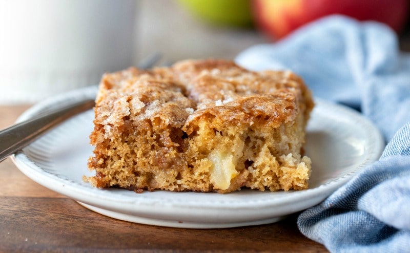 Slice of cinnamon apple cake next to a blue linen napkin