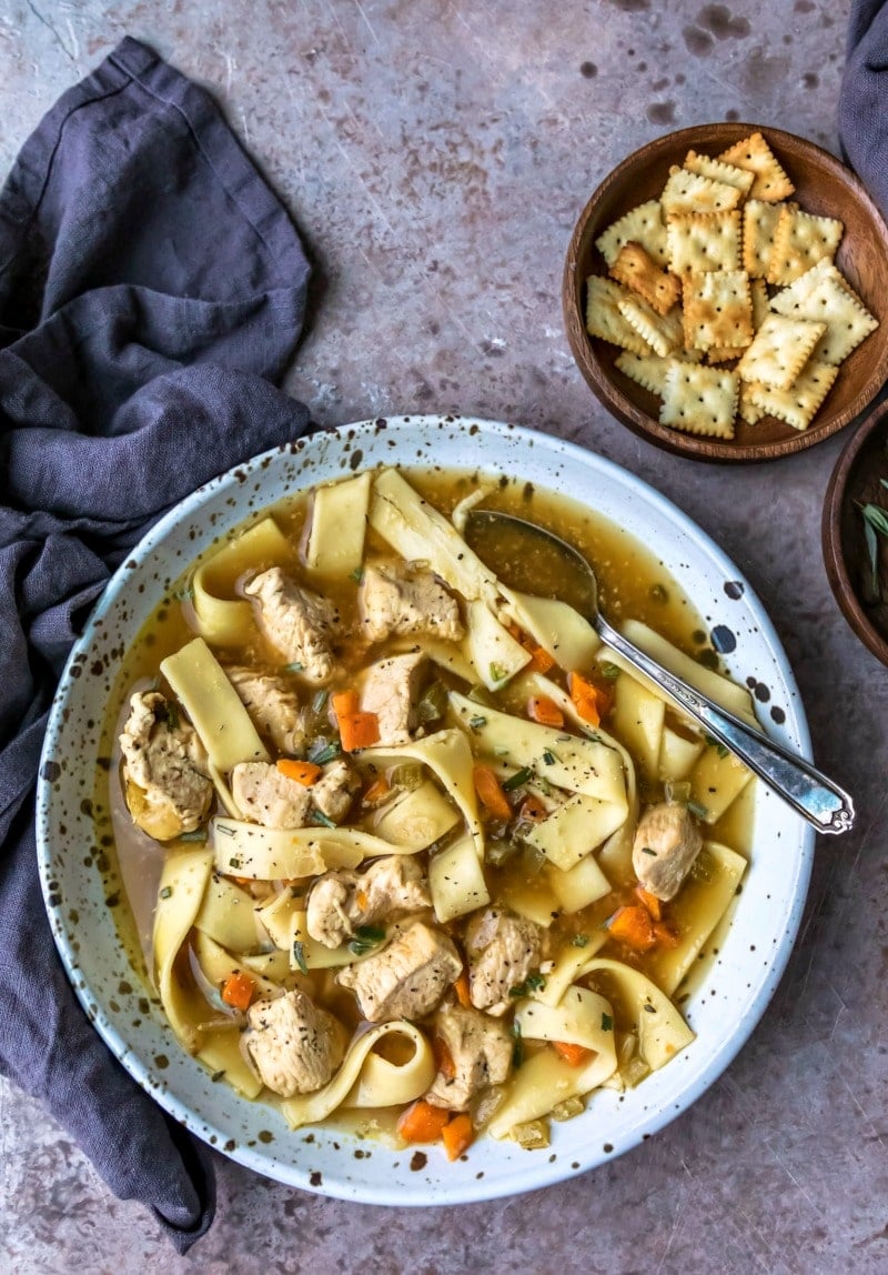 Dish of homemade chicken noodle soup next to a bowl of crackers