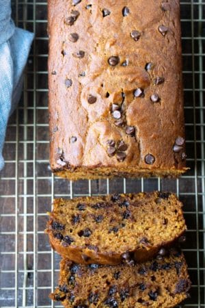 Two slices of pumpkin chocolate chip bread next to the loaf.