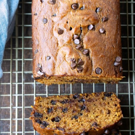 Two slices of pumpkin chocolate chip bread next to the loaf.