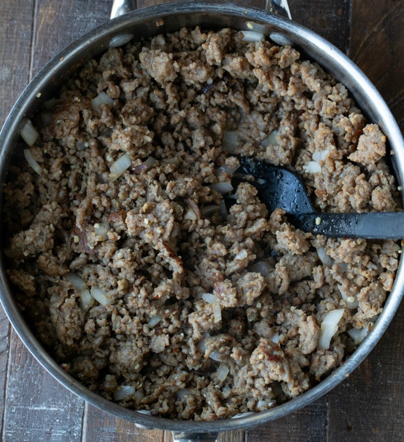 Cooked onion garlic and Italian sausage in a silver skillet