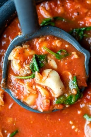 Ladle holding a scoop of slow cooker tortellini soup