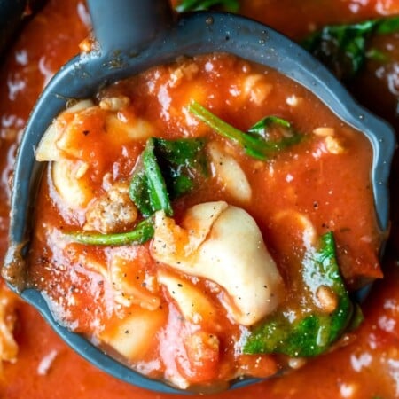 Ladle holding a scoop of slow cooker tortellini soup