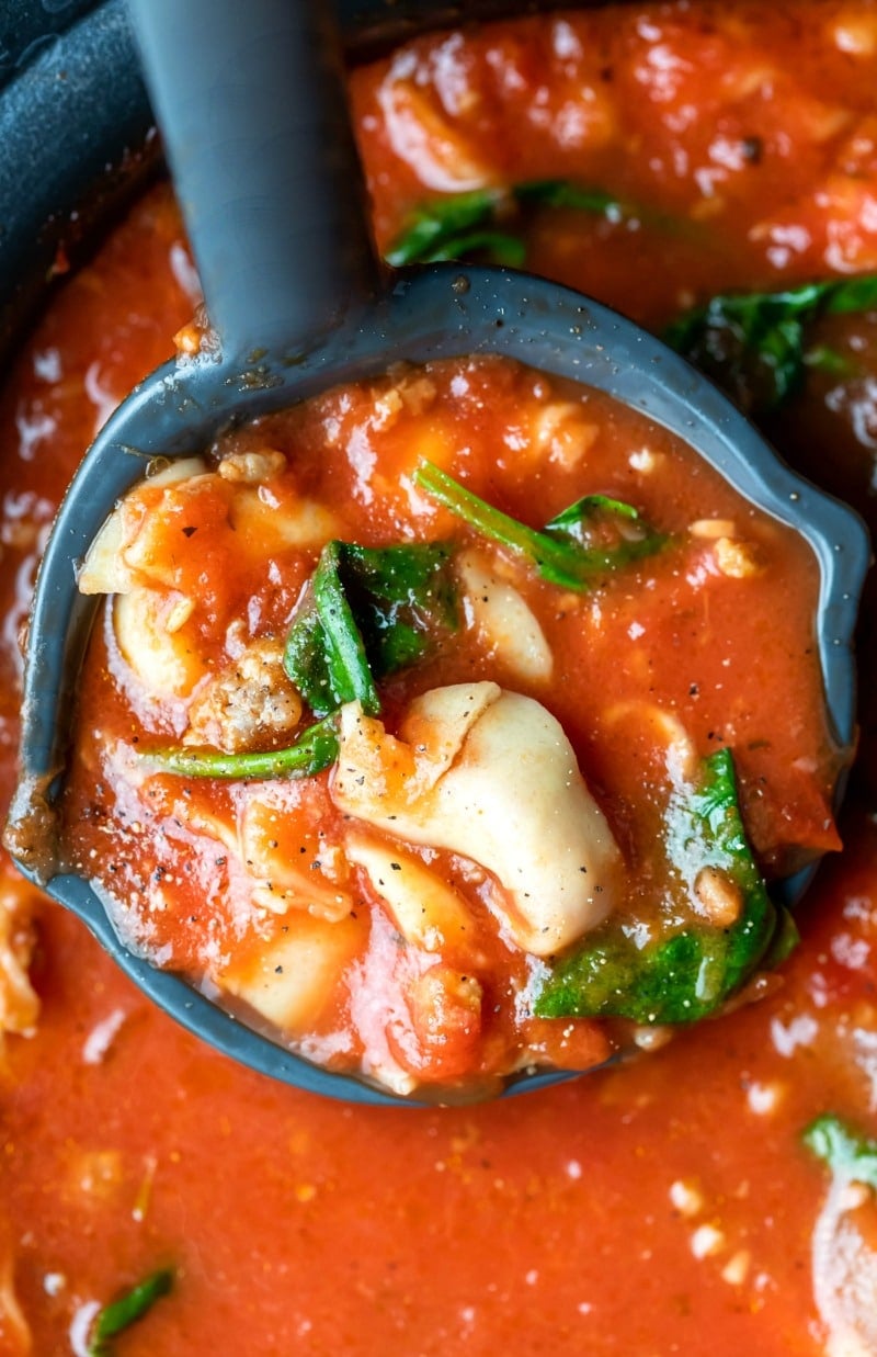 Ladle holding a scoop of slow cooker tortellini soup