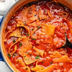 A blue cast iron Dutch oven filled with lasagna soup.