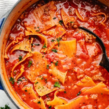 A black spoon in a pot of lasagna soup.