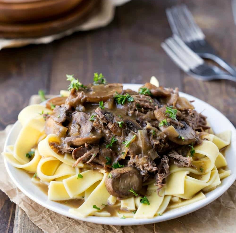 Crockpot Beef Tips over egg noodles on a white plate