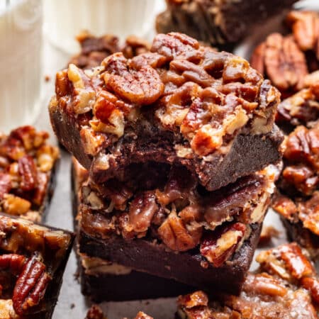 A couple of pecan pie brownies in a stack with a bite missing from the top brownie.