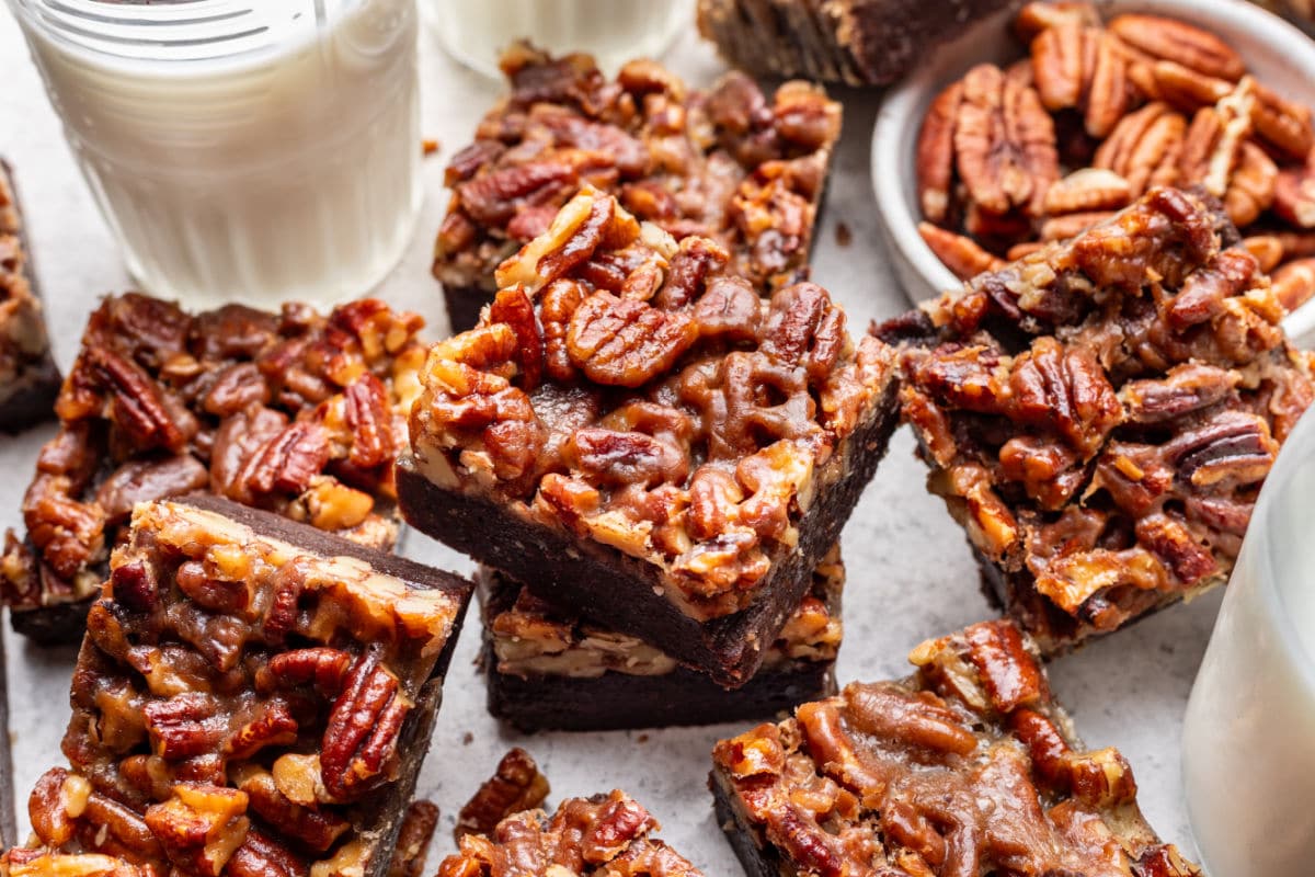 Cut pecan pie brownies next to a glass of milk.