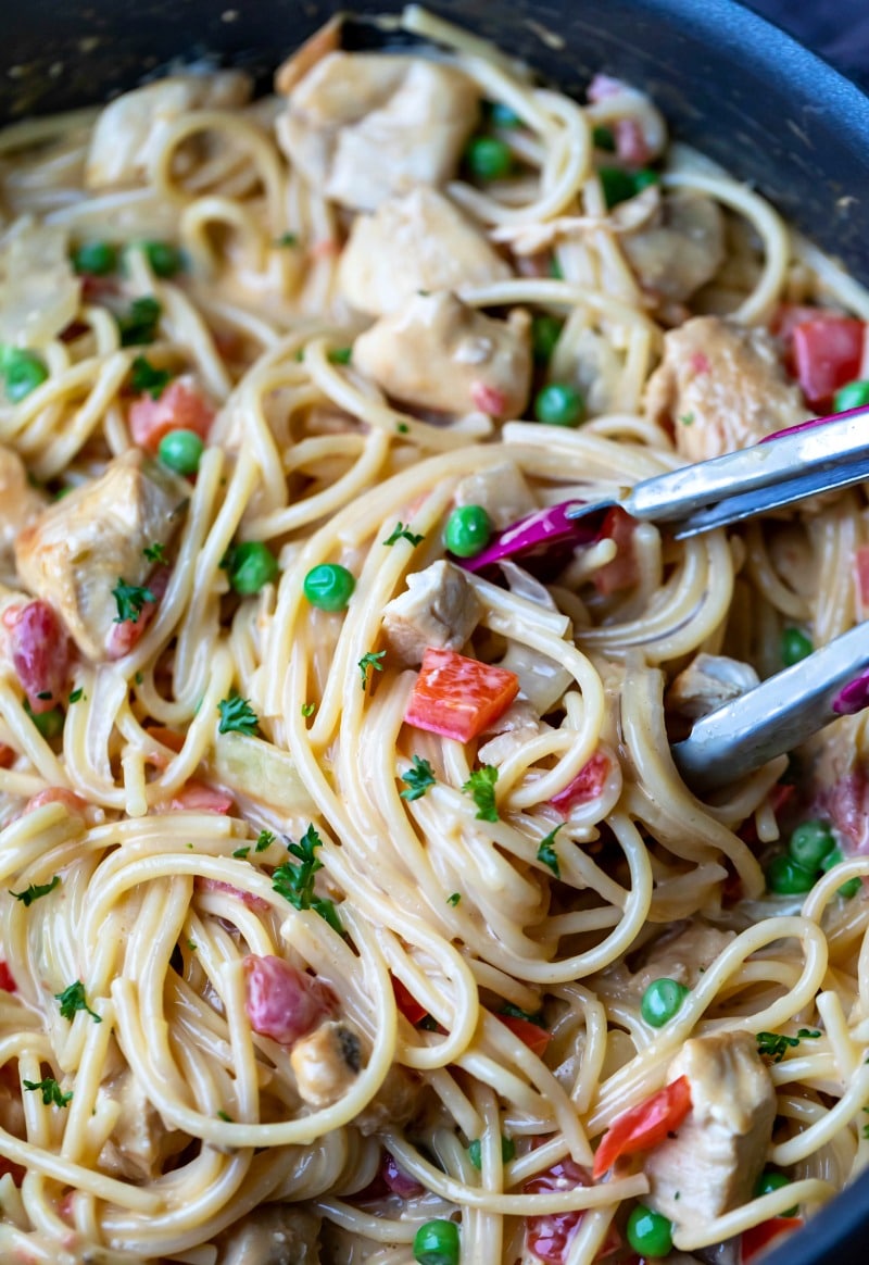 Tongs pulling chicken spaghetti from a pot