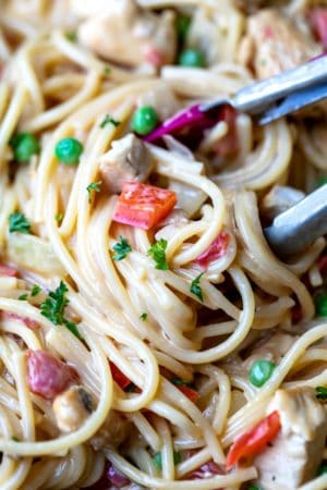 Tongs pulling up a scoop of chicken spaghetti