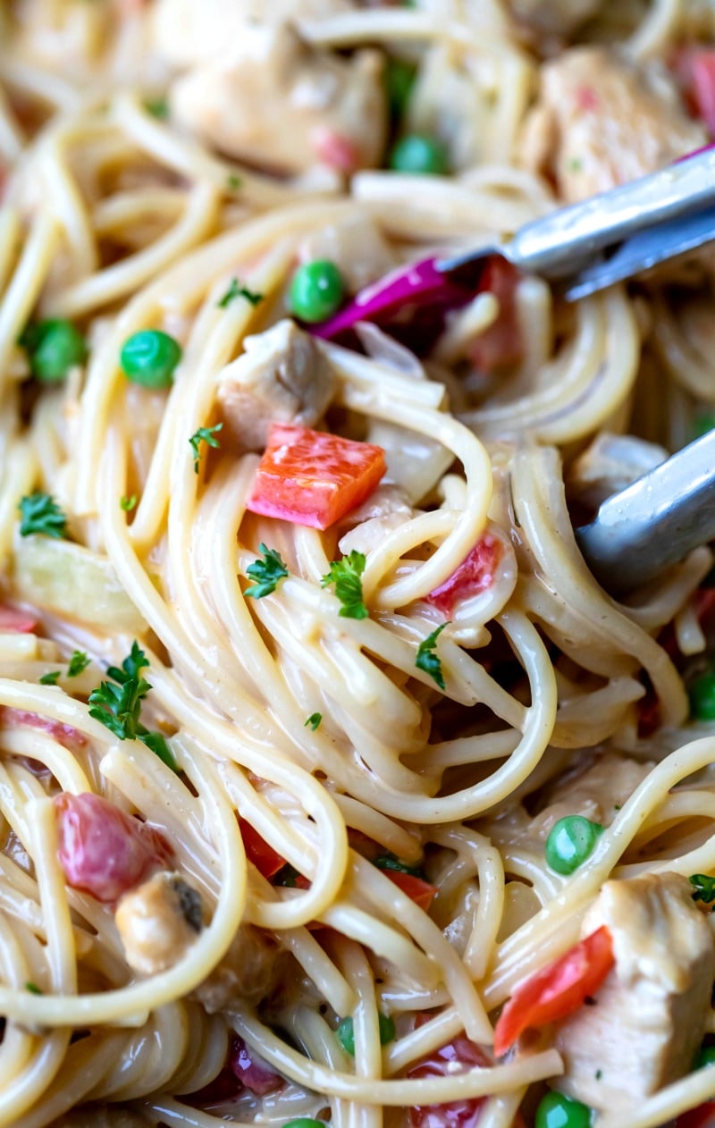 Tongs pulling up a scoop of chicken spaghetti