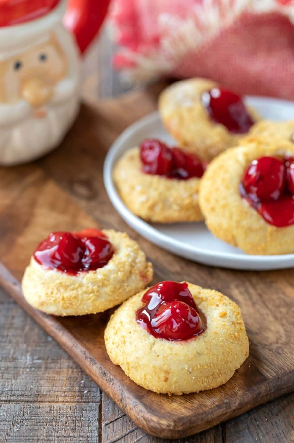 Cherry cheesecake thumbprint cookies next to a santa mug.