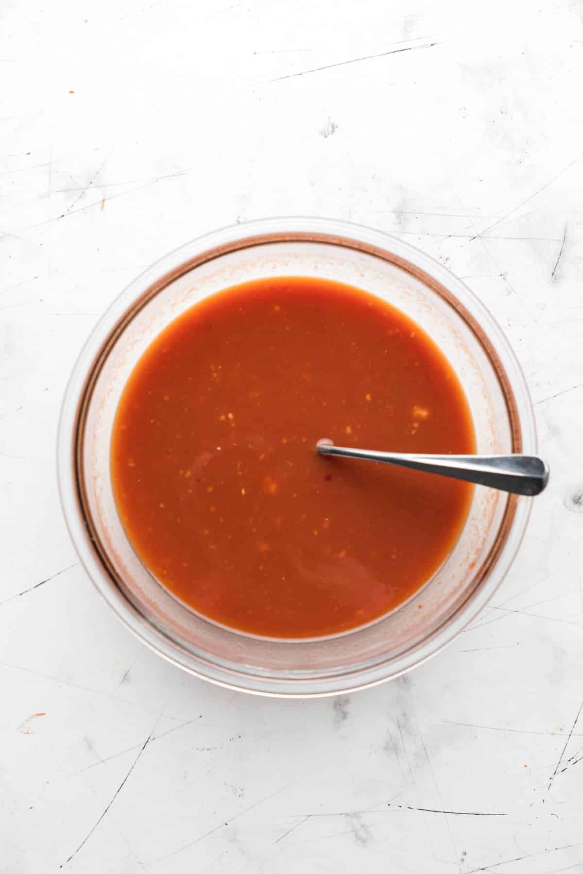 Sauce for orange chicken in a glass bowl.